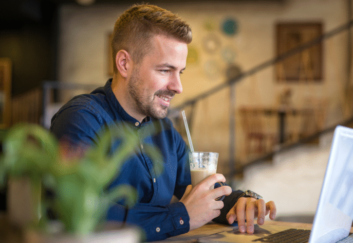 Mężczyzna pracuje w kawiarni, prowadzi rekrutację online.